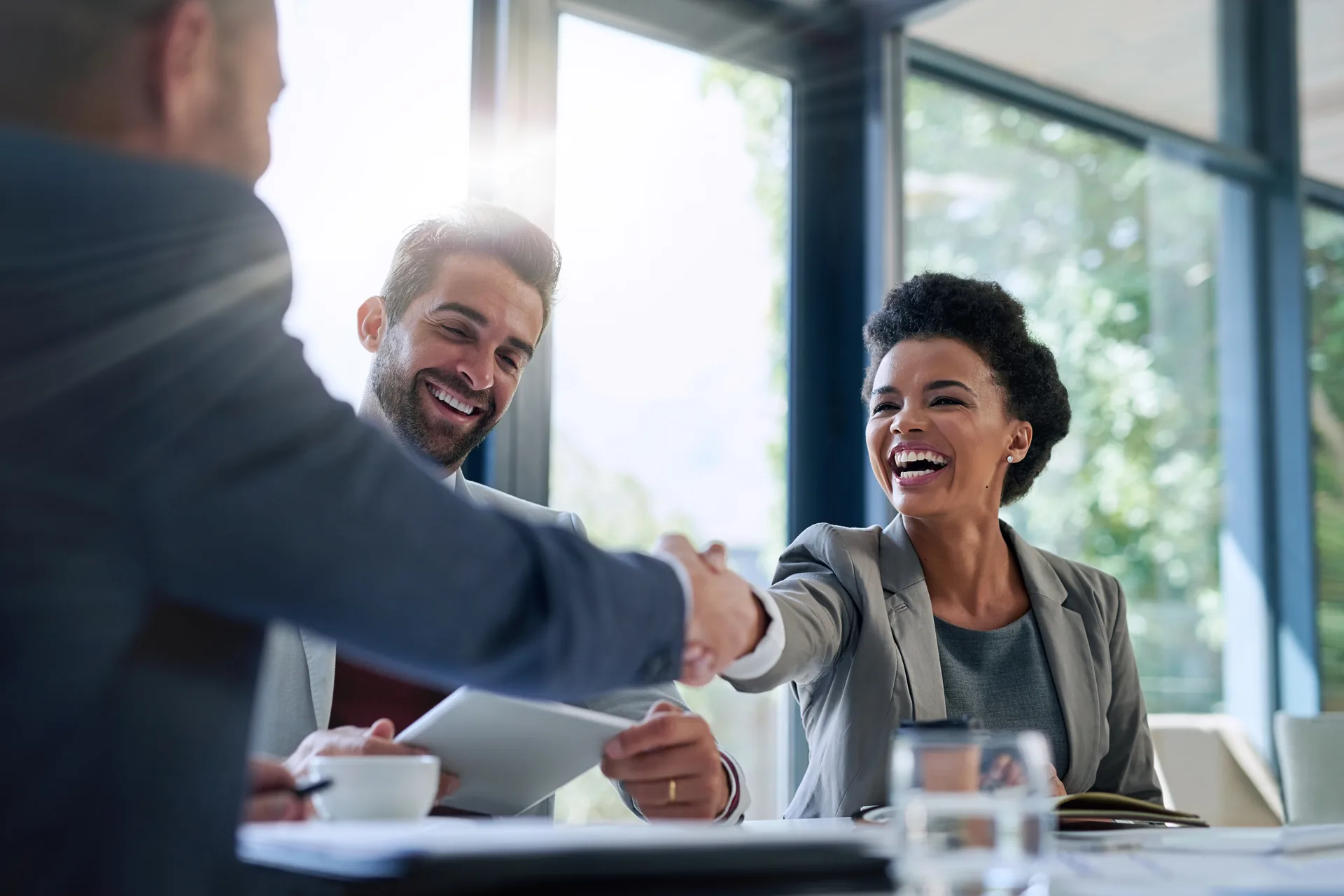 Two business partners shaking hands across a table during a friendly meeting